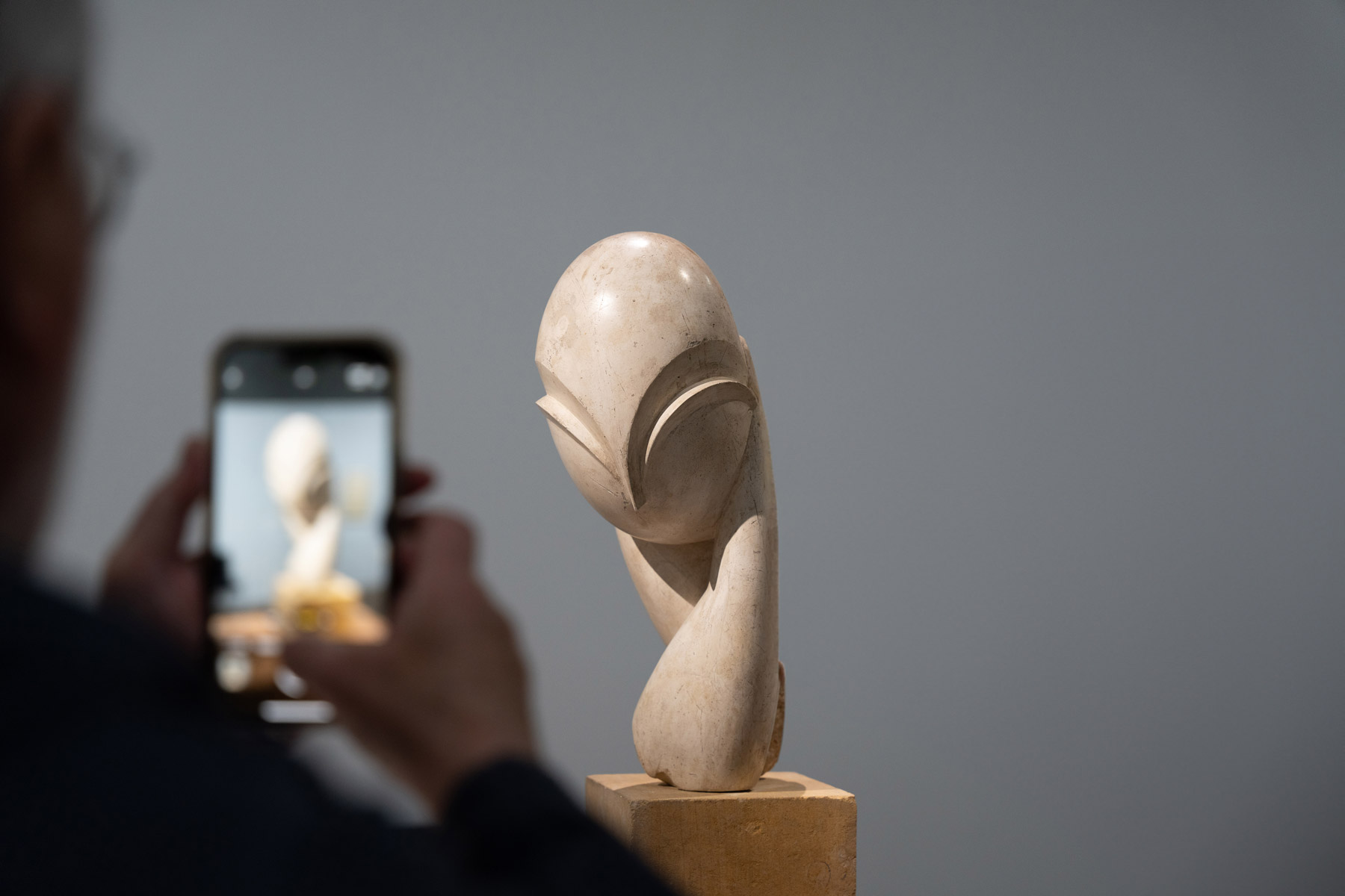 A man is taking a picture of “Mlle Pogany II” by Constantin Brâncuși. Image from the exhibition “Constantin Brâncuși” at the Center Pompidou 2024 © Photography by Sarah Dorweiler / Aesence